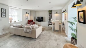Ein modernes Wohnzimmer mit Sofa, Fernseher und Essbereich.