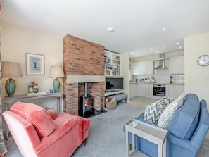 A living room with a fireplace, a sofa, a coffee table, and a blue couch. - 1 bedroom accommodation in Doxford, near Embleton (Doxford, near Embleton)
