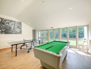 A pool table with a green felt surface, a ping pong table, and a cityscape mural on the wall.