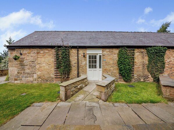 A stone building with a white door, a small porch, and ivy-covered walls.