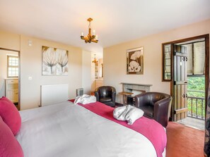 A hotel room with a bed, two leather chairs, a fireplace, and a balcony with a view. - 4 bedroom accommodation in Windermere (Windermere)