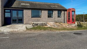 Una casa a due piani con facciata in pietra, una cabina telefonica rossa e un vialetto lastricato.