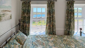 Una camera da letto con un letto, due finestre con tende e vista sull'esterno.