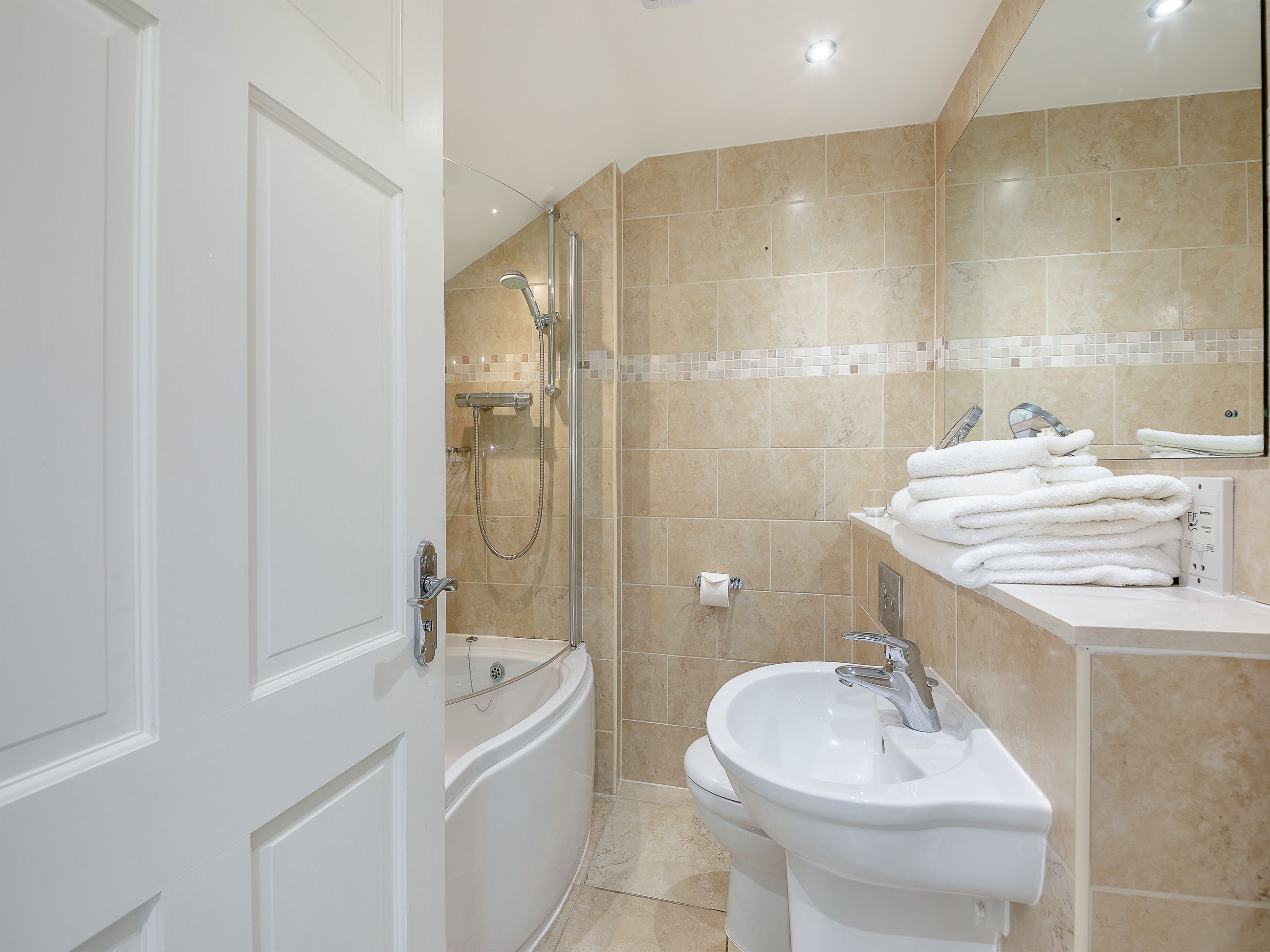 A modern bathroom with a bathtub, shower, sink, and a mirror.