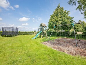 A playground with a slide, swings, and a climbing structure. - 1 bedroom accommodation in Doxford, near Embleton (Doxford, near Embleton)