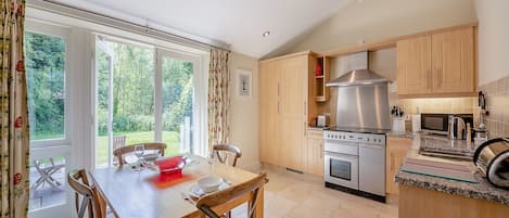 Una cocina con armarios de madera, una estufa de acero inoxidable y un comedor con mesa y sillas.