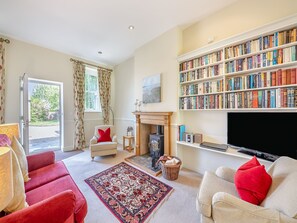 A living room with a fireplace, a bookshelf, a television, and a red armchair.