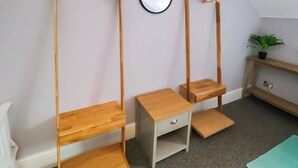 Ein Zimmer mit einer Holzhängeregalschrank, einem kleinen Schreibtisch und einem Wandspiegel.