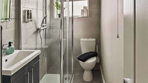 Ein modernes Badezimmer mit Duschkabine aus Glas, Toilette und Waschbecken mit Spiegel darüber.