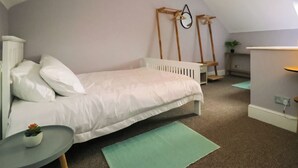 Ein Schlafzimmer mit einem Einzelbett, einem Nachttisch, einer kleinen Pflanze und einer am Holz wandmontierten Leiter.