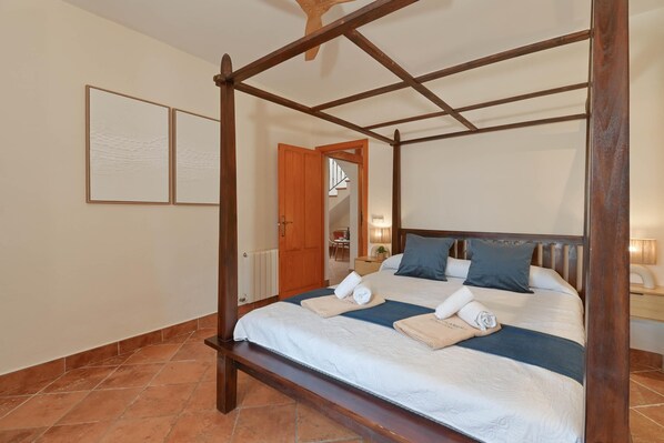 A four-poster bed with a wooden frame, a white bedspread, and two pillows. There is a wooden bench at the foot of the bed. - Riu Rau - Javea, Costa Blanca (Javea)