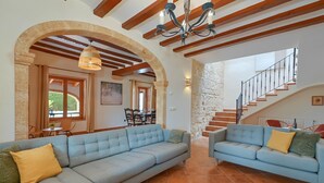 Amplia sala de estar con un sofá grande azul claro, un sofá más pequeño y una escalera que sube a un piso superior.