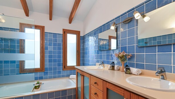 Un baño con dos lavamanos, una bañera y un espejo grande.