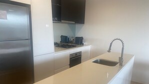Een moderne keuken met een roestvrijstalen koelkast, een inbouwoven, een wastafel met een bijzondere kraan en een koffiezetapparaat op het aanrecht.