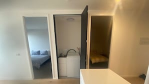 Een knus kamertje met een bed, een kleine kitchenette en een badkamer.