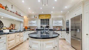 A spacious kitchen with a large island, white cabinetry, stainless steel appliances, and a variety of kitchenware.