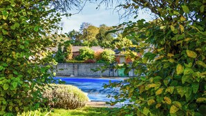 A garden with a water feature, surrounded by lush greenery and a stone wall.