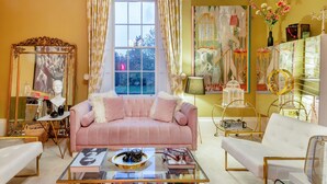 A cozy living room with a pink sofa, a glass coffee table, and a white armchair.