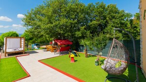Ein Garten mit Schaukel, Spielbereich und Hängematte.