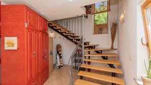 A staircase with wooden steps and metal railings, leading to a landing with a red cabinet and a framed picture.
