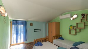 Una habitación con dos camas, un armario, un espejo y una ventana con cortinas.