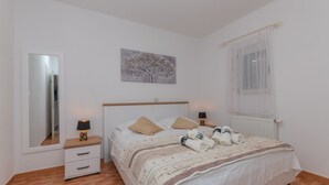 A bedroom with a bed, a nightstand, a mirror, a window with curtains, and a wall-mounted picture. - Villa Ana - Makarska by Villas Guide (Makarska)