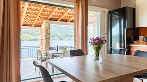 A dining area with a table, chairs, a vase of flowers, and a view of a lake. - Holiday home Erika by Villas Guide (Vela Luka)
