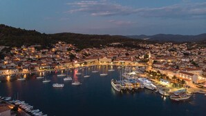 Un pueblo costero con un puerto deportivo lleno de barcos, rodeado de edificios residenciales y un paisaje montañoso de fondo.