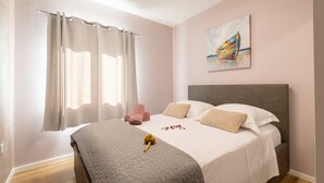 Un dormitorio con una cama, cortinas, un cuadro y un ramo de flores.