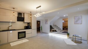 A modern kitchen with built-in appliances, a staircase leading to a dining area, and a minimalist design.