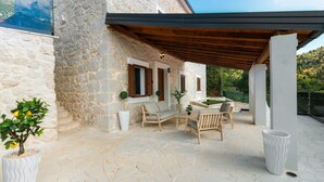 A stone building with a covered patio area featuring outdoor furniture and a view of the surrounding landscape.