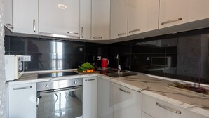 A modern kitchen with white cabinets, a built-in oven, and a stainless steel sink. - Apartman Max 3 by Villas Guide (Rijeka)
