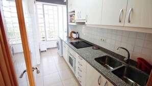 A kitchen with white cabinets, a granite countertop, a double sink, and a microwave.