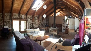A rustic interior with stone walls, wooden beams, a stone fireplace, a sofa, and a dining table. - Organic and eco-friendly B&B du Besset (Yssingeaux)