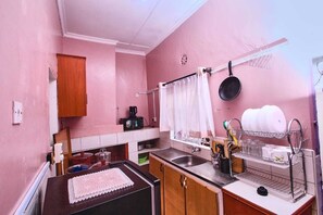 Een koelkast, een microgolfoven, kookgerei, borden en bestek