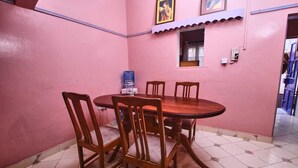 A dining area with a round wooden table and four chairs, pink walls, and a tiled floor. - Lux Suites The Pink House Naivasha (Naivasha)