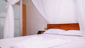 A neatly made bed with white linens and a white towel on the side. - Lux Suites The Pink House Naivasha (Naivasha)