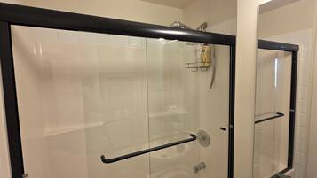Una cabina doccia in vetro con cornice nera, porta in vetro e soffione a parete.