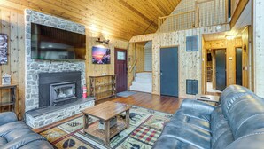 A cozy cabin interior with a stone fireplace, leather sofa, and a staircase leading to an upper level. - Serene Mountain Home: 11 Mi to Gettysburg (Fairfield)