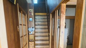 A wooden hallway with a checkered floor leading to a staircase. - Tsukiyama Inn (Yamatotakada)