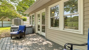 A covered deck with a chair and a small table, a shed, and a large window overlooking a yard. - Riverfront Fun: Quiet Home Near Hampton Coastline (Hampton)