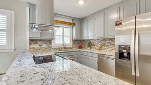A modern kitchen with granite countertops, stainless steel appliances, and light gray cabinetry. - Riverfront Fun: Quiet Home Near Hampton Coastline (Hampton)