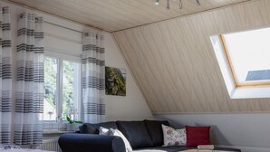 A modern loft bedroom with a sloped ceiling, a large window, a sofa, a bed, and a wooden coffee table. - Vacation Rental in Winningen with a View of the Moselle (Winningen)