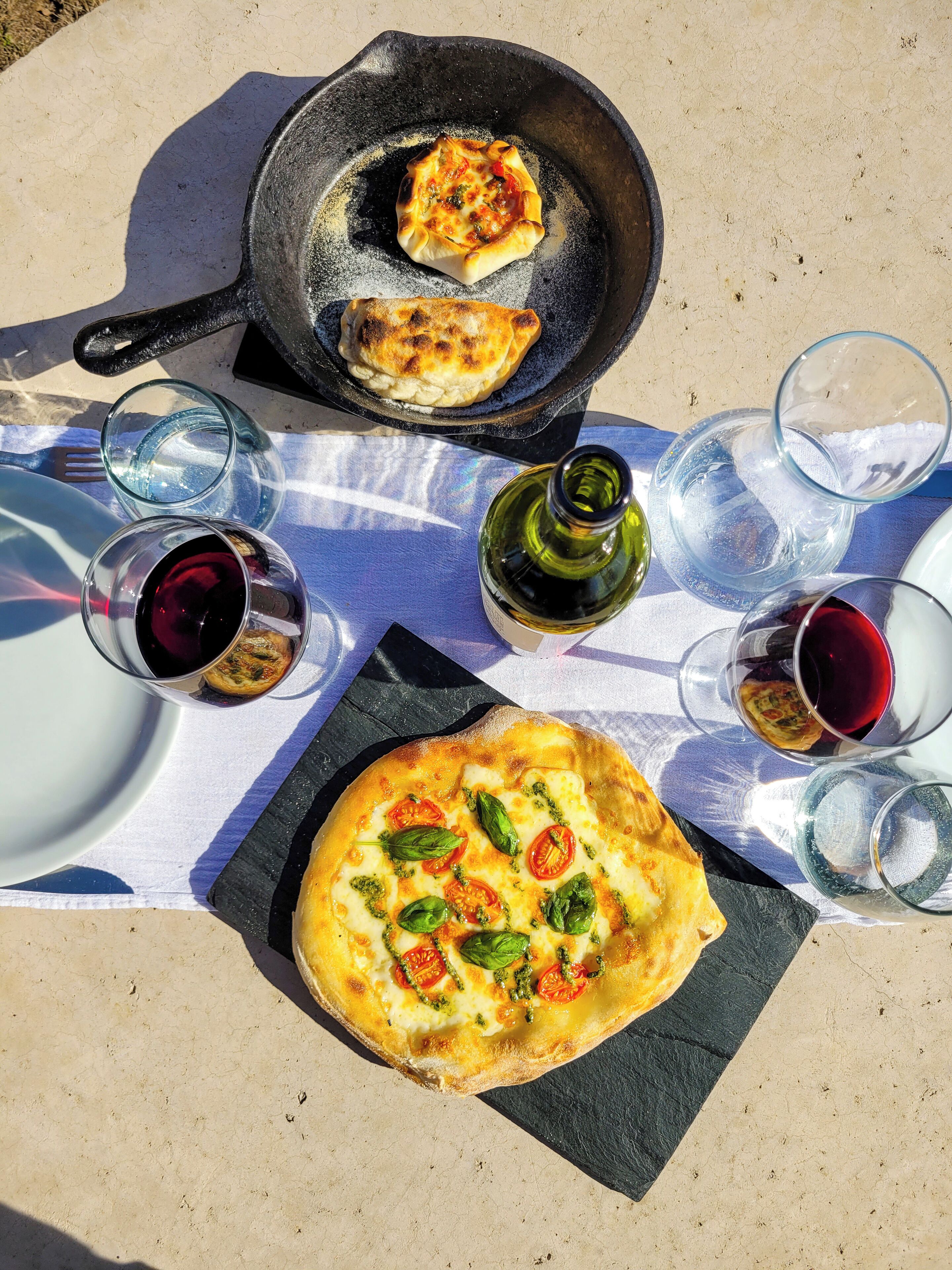 Pizza en een pan met een klein schaaltje op een buitentafel.