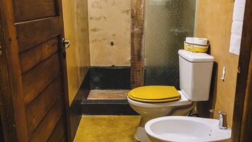 A small, narrow bathroom with a wooden door, a yellow toilet, a white sink, and a towel hanging on the wall.