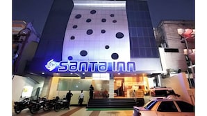 En byggnad med en stor, upplyst skylt som visar texten ”SANTA INN”, och en rad parkerade motorcyklar framför.