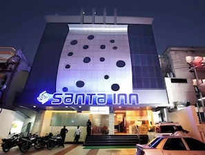 A building with a large illuminated sign reading "SANTA INN" and a row of parked motorcycles in front.