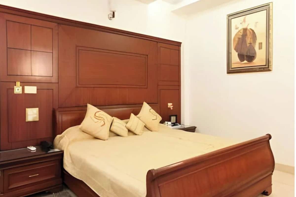 A bedroom with a wooden bed, a nightstand, a bedside table, and a framed picture on the wall.