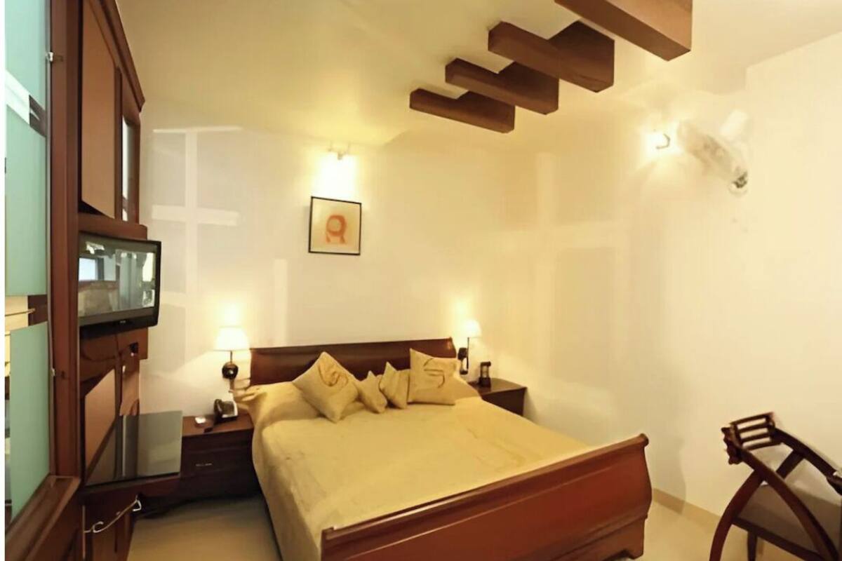 A bedroom with a wooden bed, bedside tables, a desk, and a chair.