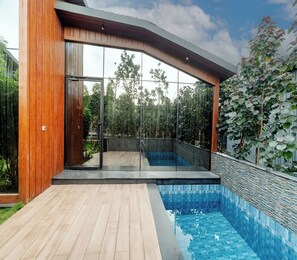 A modern house with a swimming pool, wooden deck, and glass doors leading to a patio. - Forrest (Mahabalipuram)